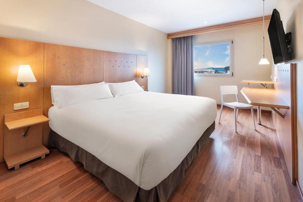 Cette chambre comprend un grand lit et un bureau. dans l'établissement B&B HOTEL Madrid Arganda, à Arganda del Rey