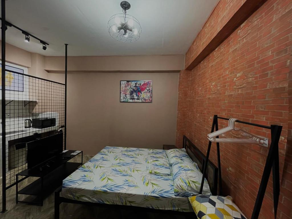 a bedroom with a bed and a brick wall at Staycation Cozy Comfortable STAY Hotel QualitY fast Internet Worldwide Channel Cable TV Gaming Netflix Sanitize in Manila