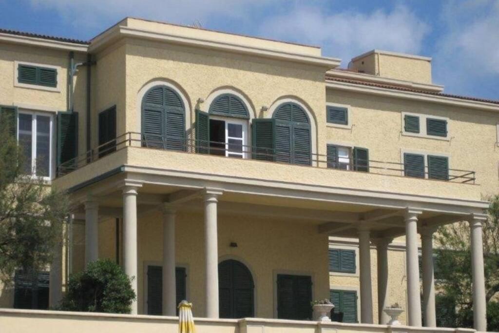 un gran edificio con un balcón en la parte superior. en APPARTAMENTO IN VILLA STORICA SUL MARE PER 8/10 PERSONE, en Castagneto Carducci