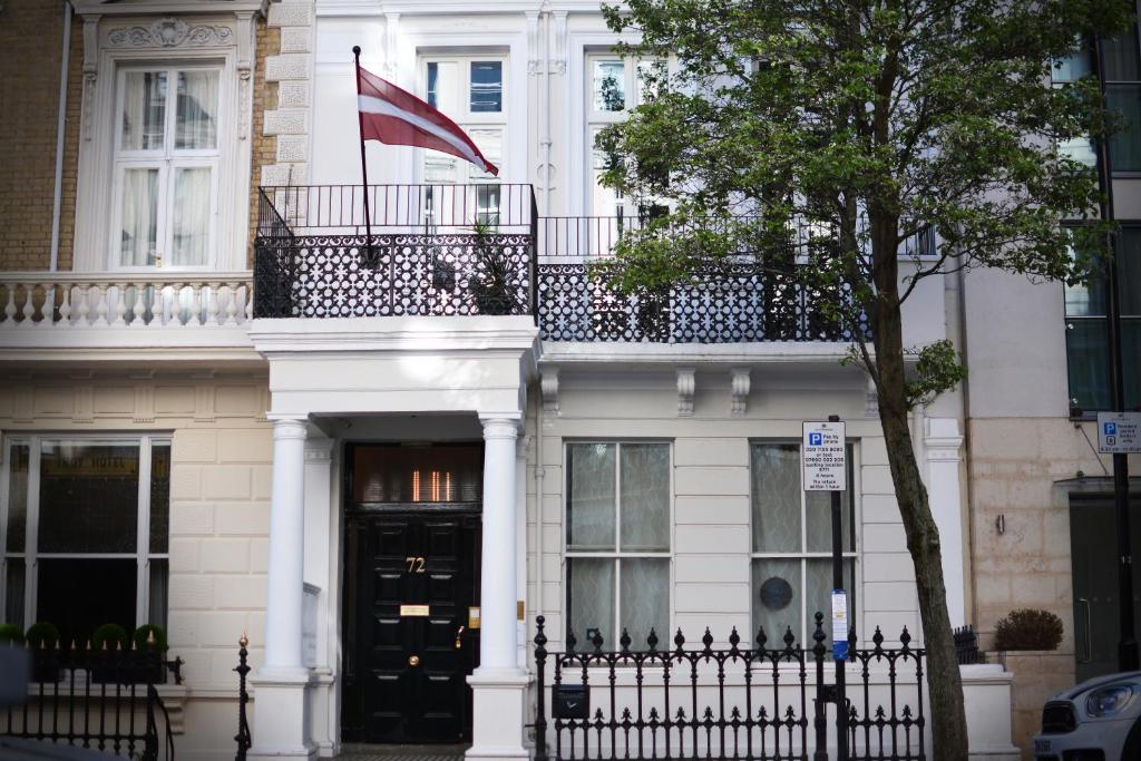 a white building with a balcony and a flag at 72QT in London