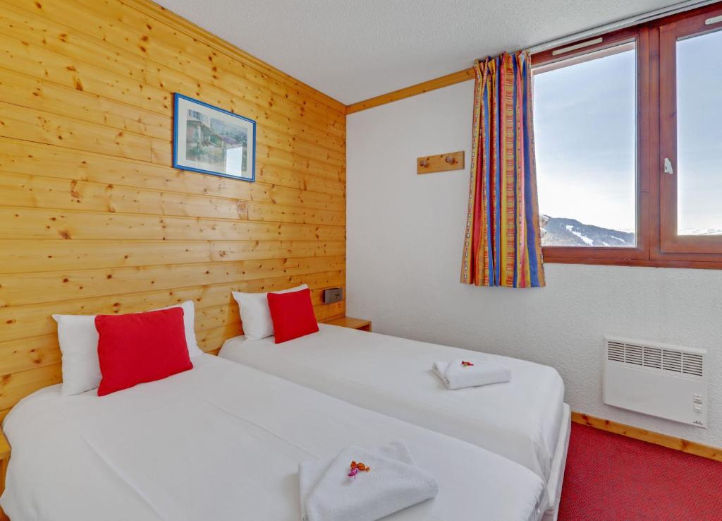- 2 lits dans une chambre dotée de murs en bois et de fenêtres dans l'établissement Hotel Emeraude, à Peisey-Nancroix