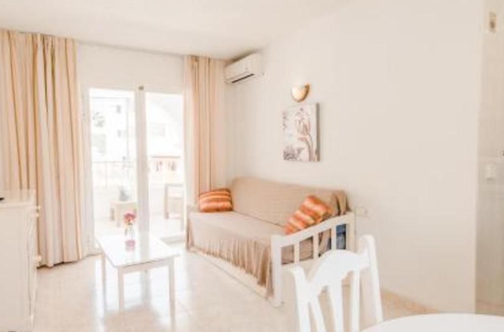 a white living room with a couch and a window at Apartamentos Torres Cardona (Playa) in Cala Llonga