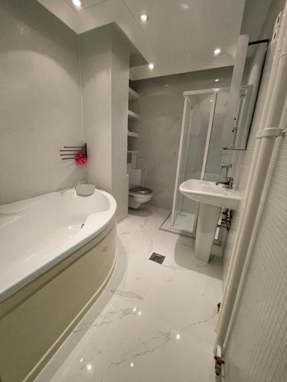 a white bathroom with a tub and a sink at Ruben Apartman City Center in Debrecen