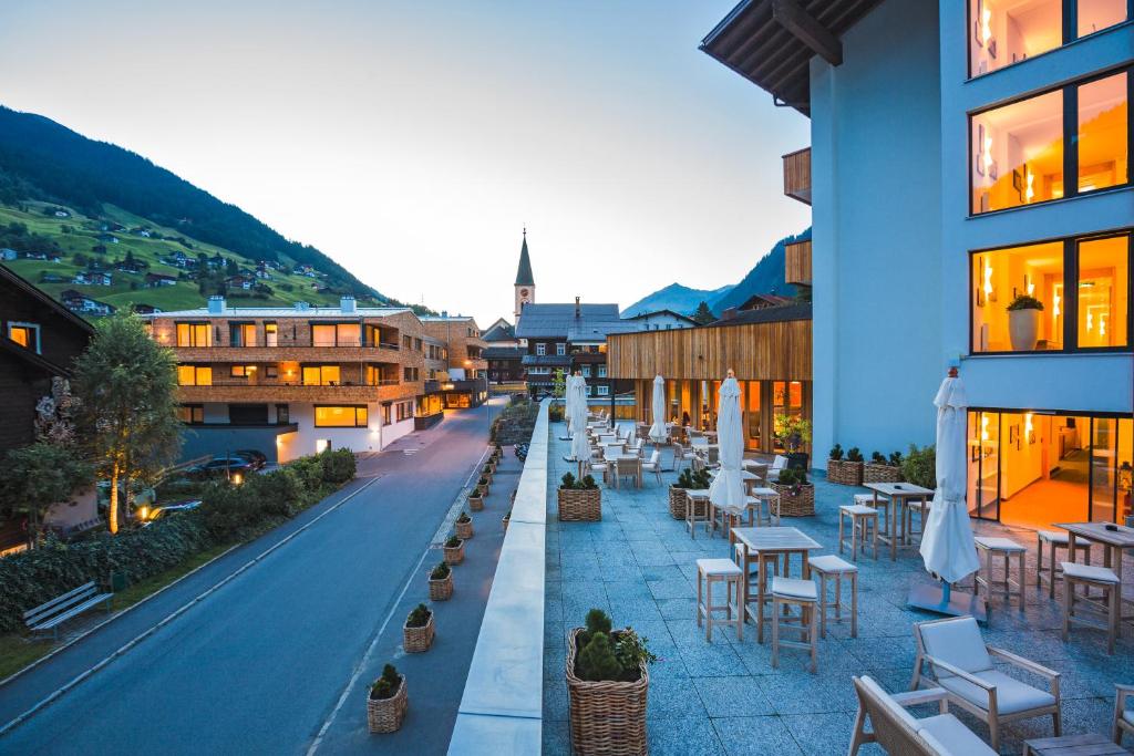 eine Stadtstraße mit Tischen, Stühlen und Gebäuden in der Unterkunft Sporthotel Chalet in Gaschurn