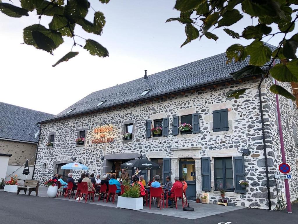 a group of people sitting outside of a stone building at Auberge du Cezallier in Montgreleix