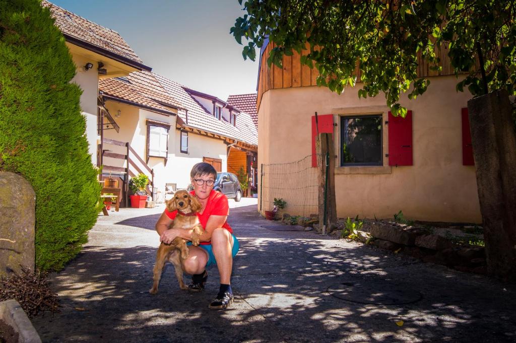 une femme tient un chien dans une rue dans l'établissement Au murier, à Goxwiller