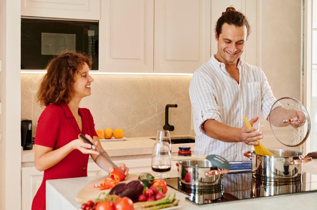 Ein Mann und eine Frau stehen in einer Küche und bereiten Essen vor. in der Unterkunft The Boc Suites in Palma de Mallorca
