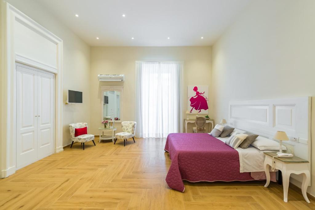 een slaapkamer met een groot bed en een paarse deken bij La Gatta Cenerentola Rooms in Napels