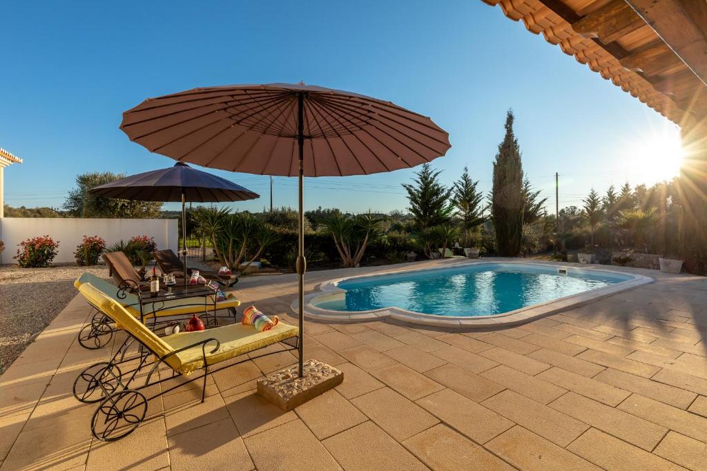 uma cadeira e um guarda-sol junto a uma piscina em Quinta das Lameiras em Lagoa