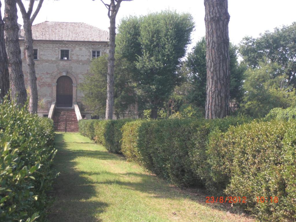 a walkway leading to a building with a door and trees at Bed and Breakfast di Charme La Bonarella in Russi