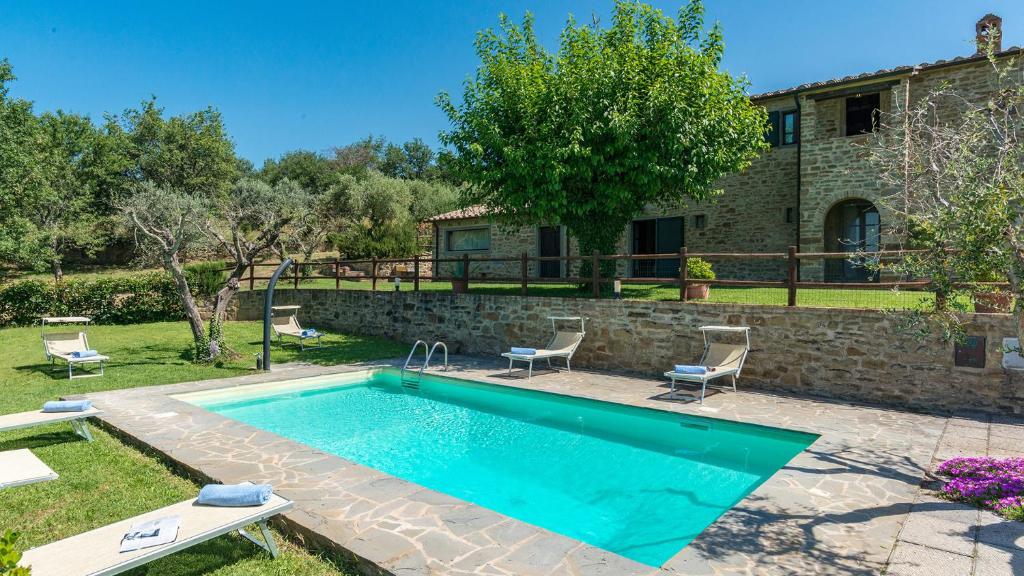 a swimming pool in front of a house at La Torretta 10 Emma Villas in Cortona