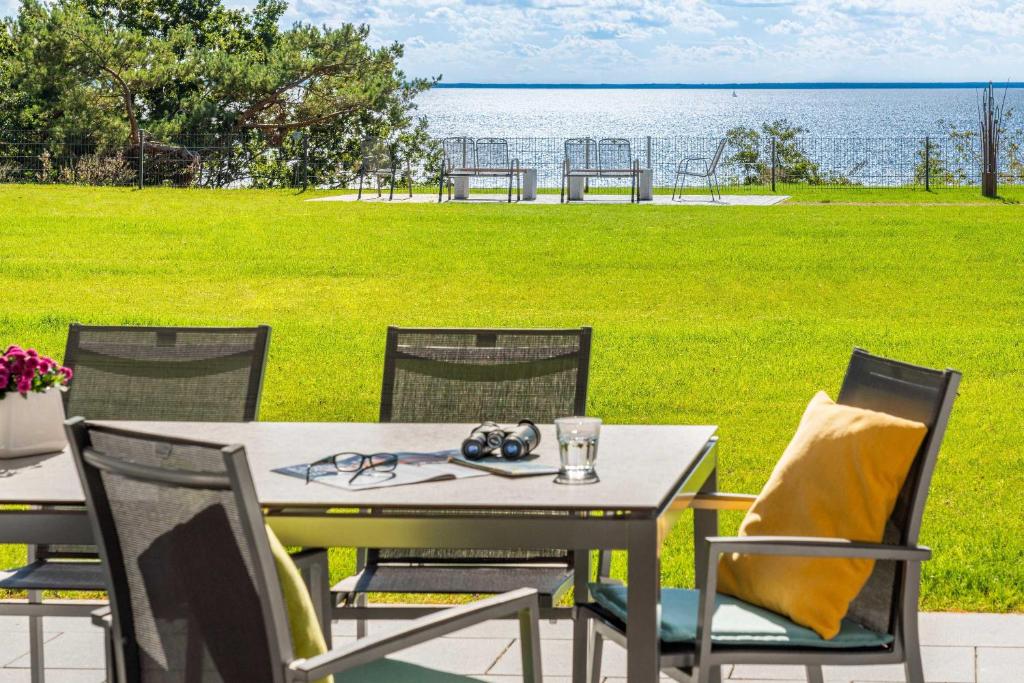 - une table et des chaises avec vue sur l'eau dans l'établissement Terrassenwohnung "Kliffgarten" - Oase am Haff, à Garz