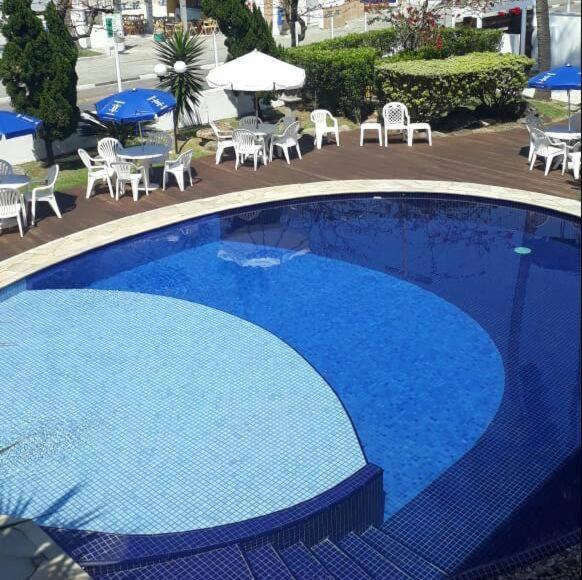 una grande piscina blu con tavoli e sedie di Charme Hotel Guarujá Frente Mar a Guarujá