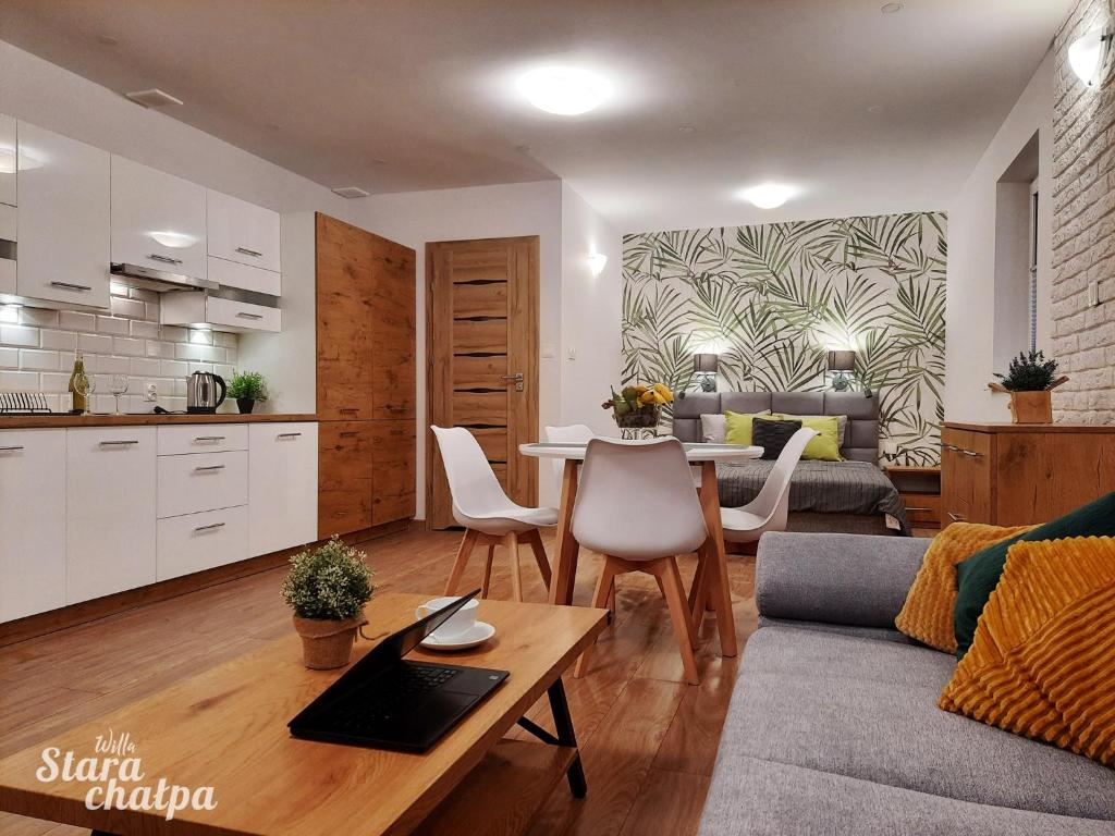 a living room with a table and a kitchen at Willa Stara Chałpa in Muszyna