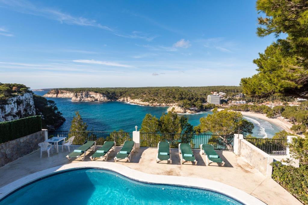 a swimming pool with chairs and a view of the water at Villa Acantilado in Ferreries