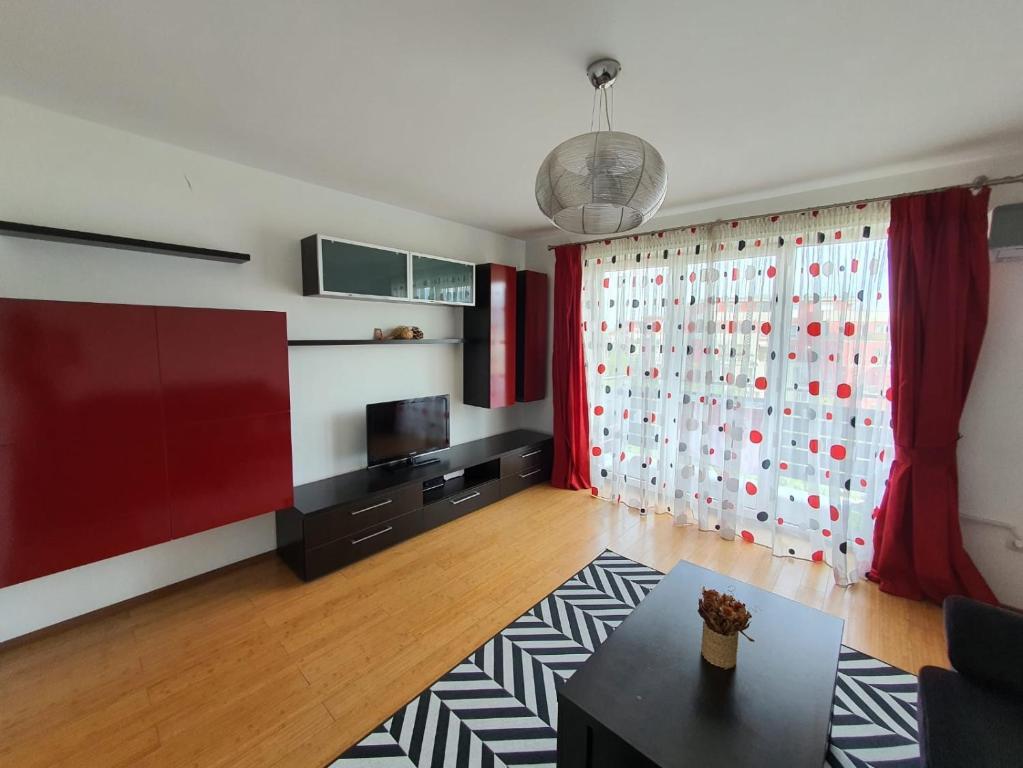 uma sala de estar com uma cortina vermelha e uma mesa em Apartment Richy Brasov em Brasov