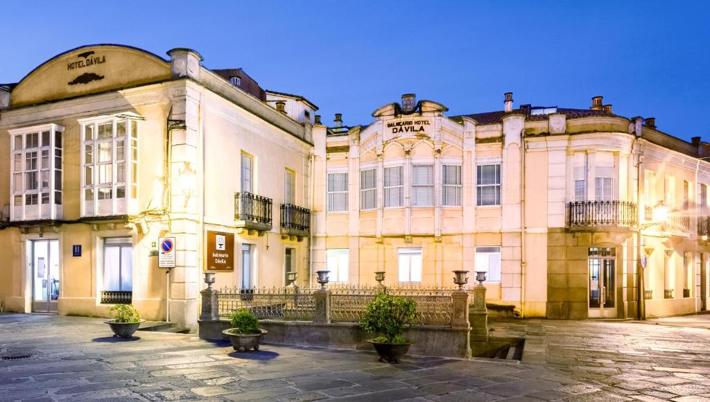 un gran edificio amarillo con macetas delante de él en Balneario Hotel Dávila, en Caldas de Reis