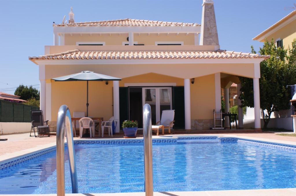 a villa with a swimming pool in front of a house at Vivenda Luz e Lúdica in Altura