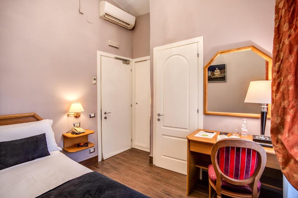Habitación de hotel con cama, escritorio y espejo. en Hotel San Valentino, en Roma