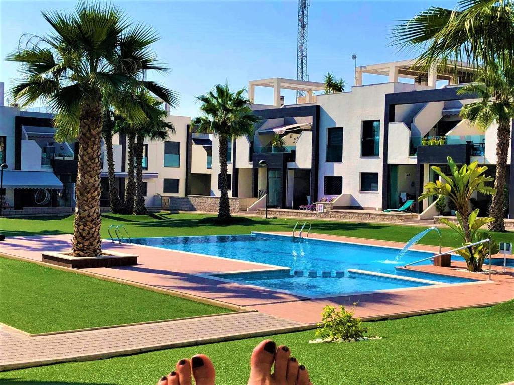 a person laying on the grass next to a swimming pool at Oasis Beach 1, La Zenia in Playas de Orihuela