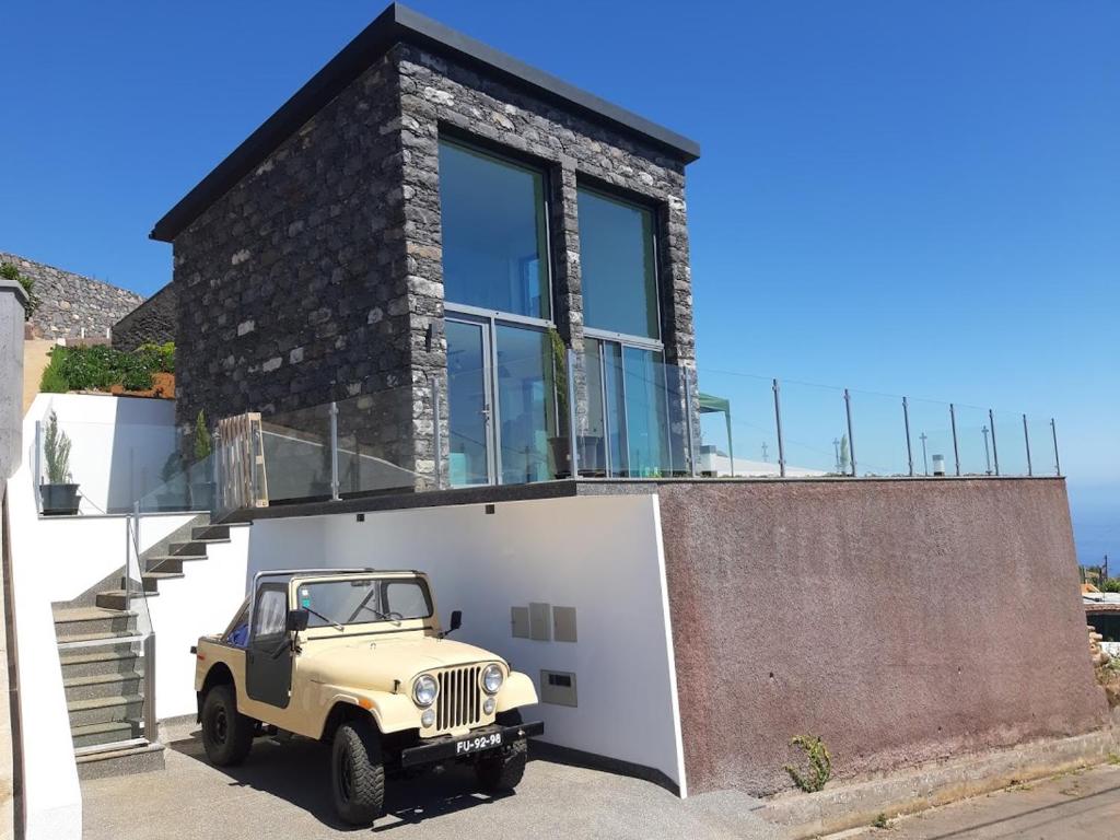 a jeep parked in front of a house at Refúgio de Pedra in Fajã da Ovelha