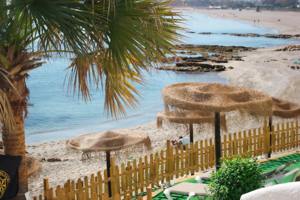 Blick auf einen Strand mit einem Zaun und Sonnenschirmen in der Unterkunft Hotel Patricia in Torreguadiaro