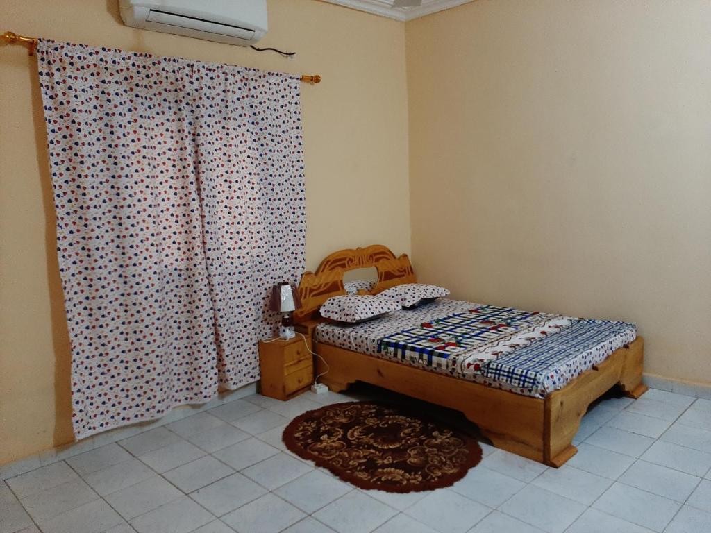 a bedroom with a bed and a curtain and a rug at Villa Chambre B climatisée douche Cuisine salon in Bamako