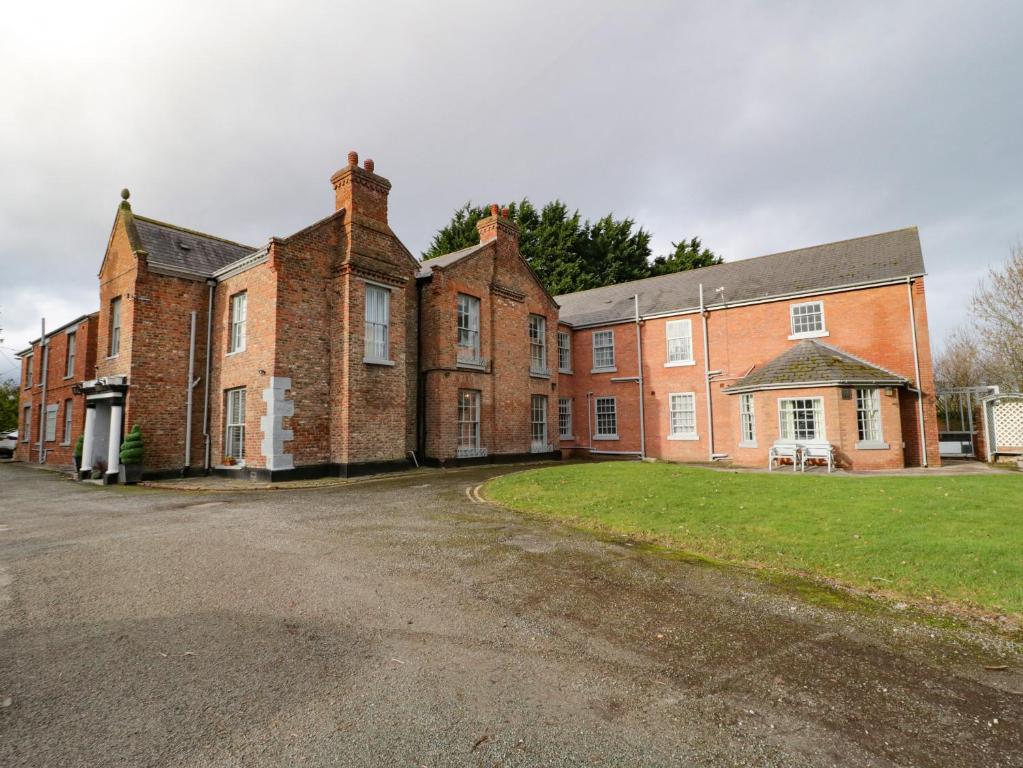 a large brick building with a grass yard in front of it at Plas Coch in St Asaph