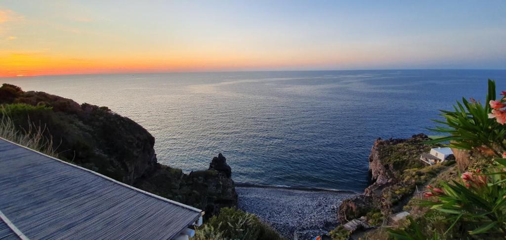 een uitzicht op de oceaan bij zonsondergang vanuit een huis bij Hotel Santa Isabel in Malfa