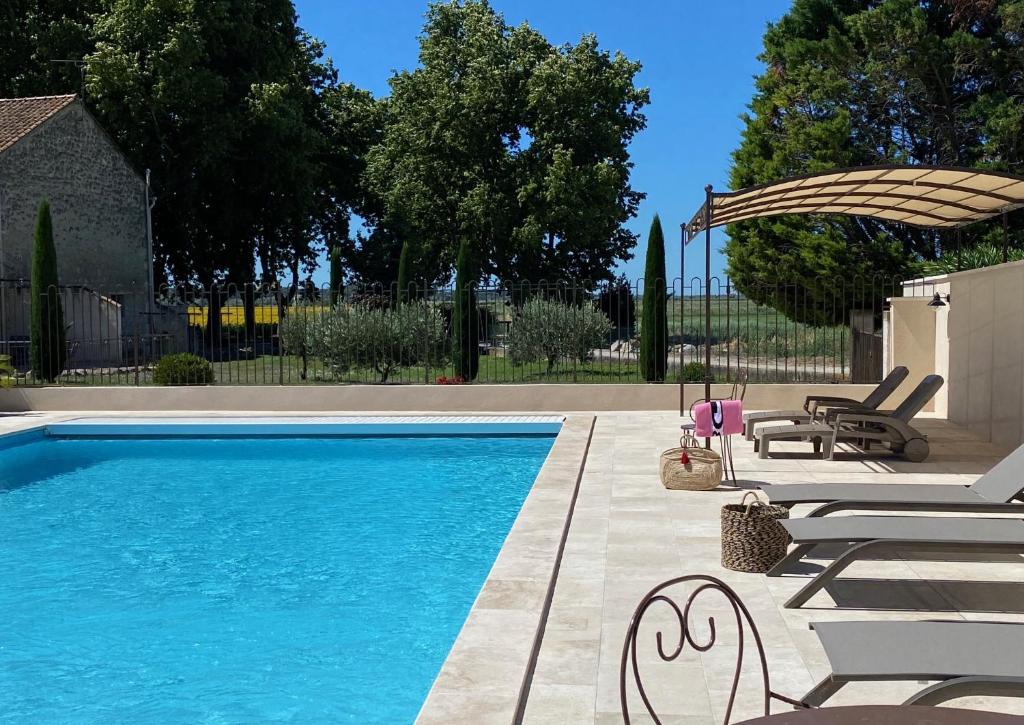 een zwembad met 2 ligstoelen en een parasol bij Le Domaine de Laforest in Fontvieille