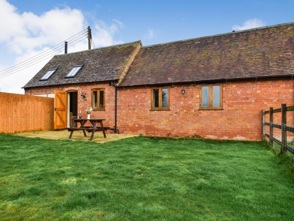 ein Backsteinhaus mit einem Picknicktisch im Hof in der Unterkunft Combine Shed in Bidford