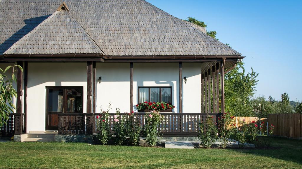 a white house with a porch and a fence at Pensiunea Tara Fagilor in Suceava