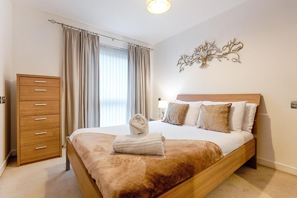 een slaapkamer met een groot bed met een houten hoofdeinde bij Royal Sovereign with Parking - TV in every Bedroom! in Swansea