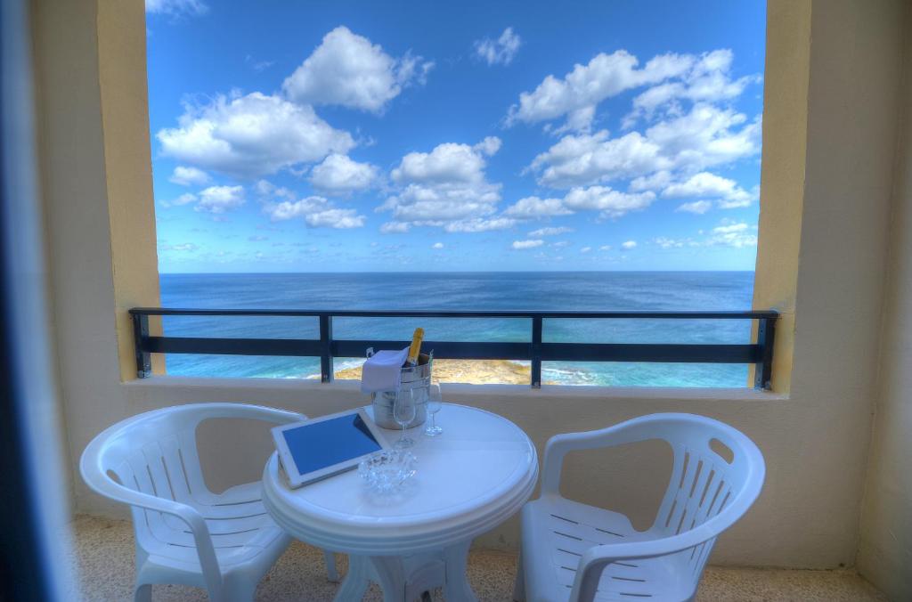 een tafel met stoelen en een laptop op een balkon met uitzicht op de oceaan bij Europa Hotel in Sliema
