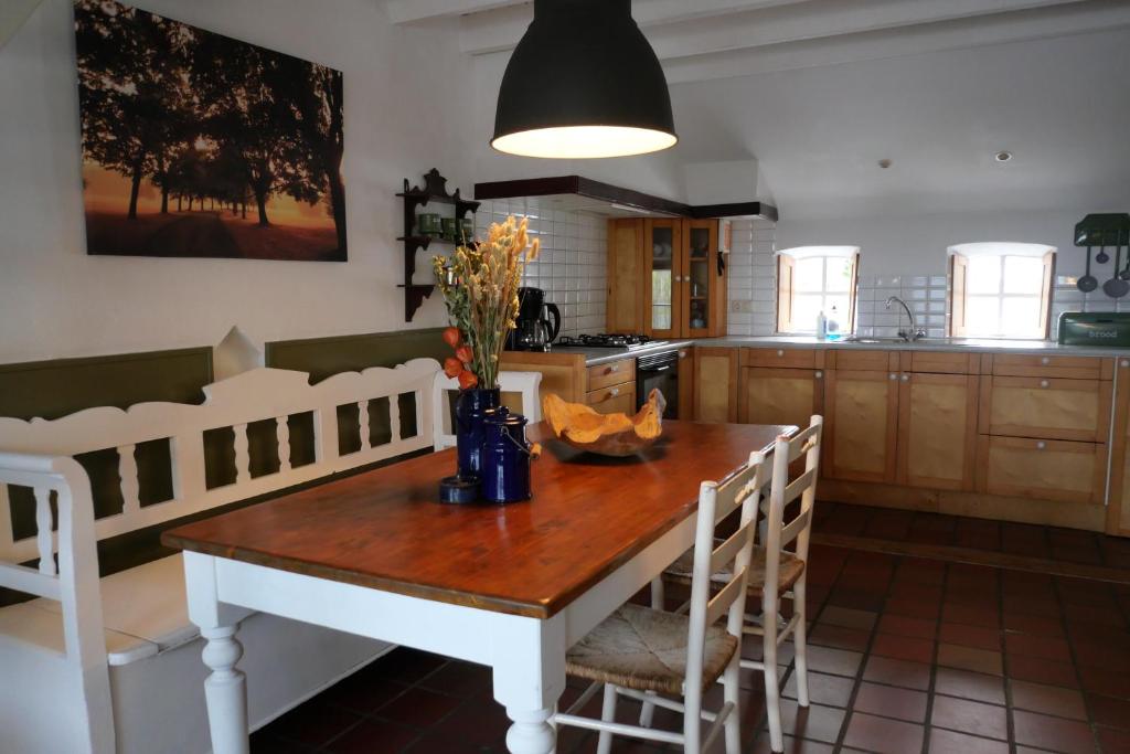 een keuken met een houten tafel met stoelen en een eetkamer bij Bergerhof de Schuur in Sevenum