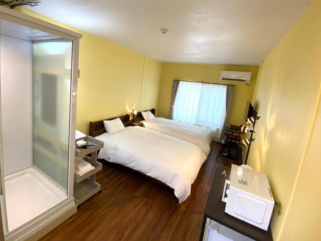 a bedroom with two beds and a glass shower at Hotel Shion no Umi - Vacation STAY 97912 in Miyako Island