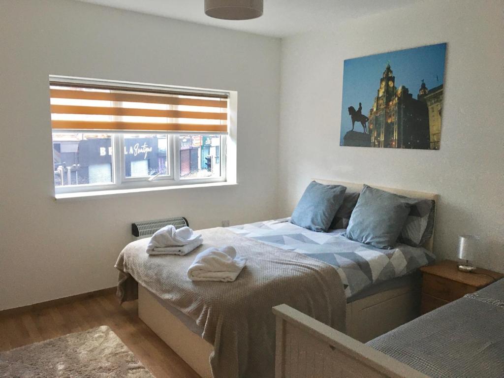 Schlafzimmer mit einem Bett und einem Fenster in der Unterkunft Flats near football clubs in Liverpool