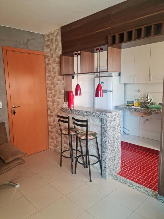 una cocina con 2 taburetes y una barra en Morro Vermelho en Goiânia