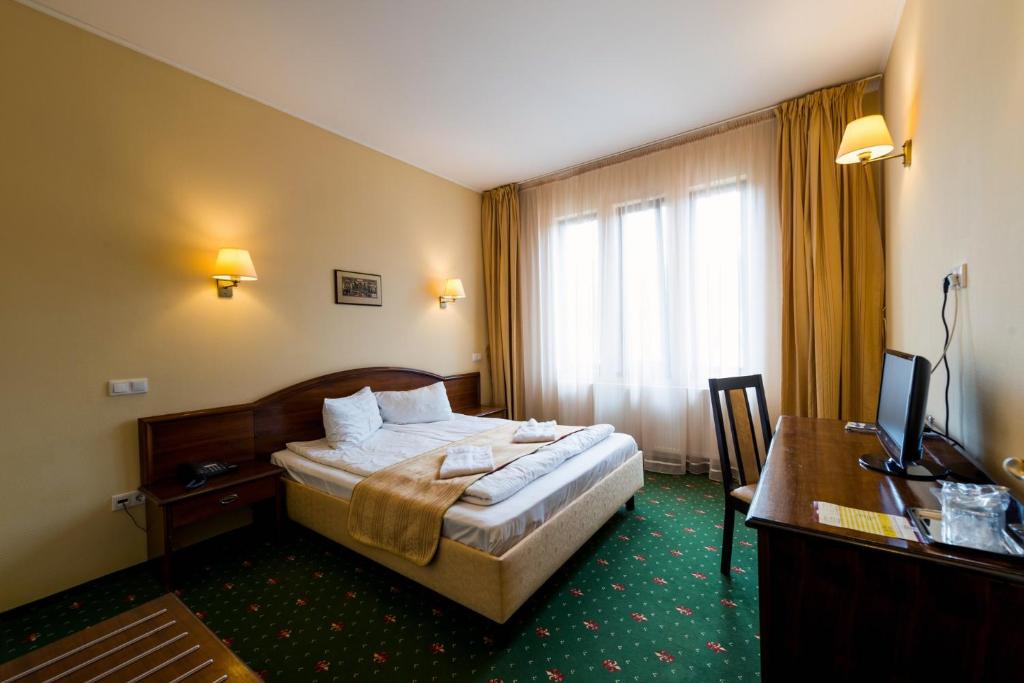 a hotel room with a bed and a desk at Coroana Brasovului in Braşov