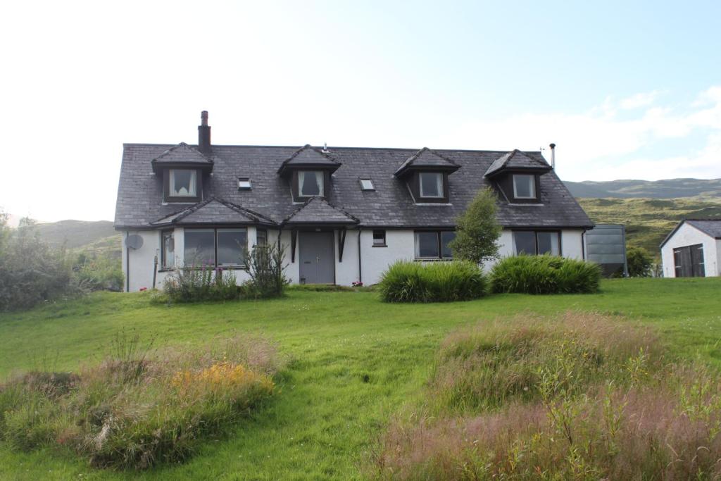 uma casa numa colina com um campo verde em Heatherbank Guest House em Strontian