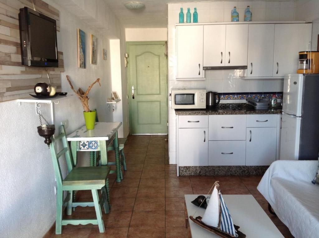 uma cozinha com armários brancos e uma mesa e cadeiras em The Studio em Benalmádena