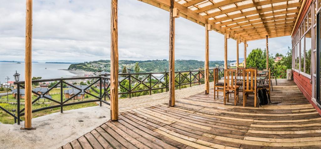 eine Holzterrasse mit einem Tisch und Stühlen darauf in der Unterkunft Hotel Boutique Antukenu in Achao