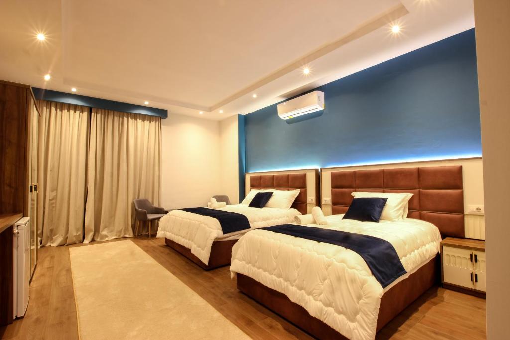 um quarto de hotel com duas camas e uma parede azul em Hotel Vasho em Gjirokastër