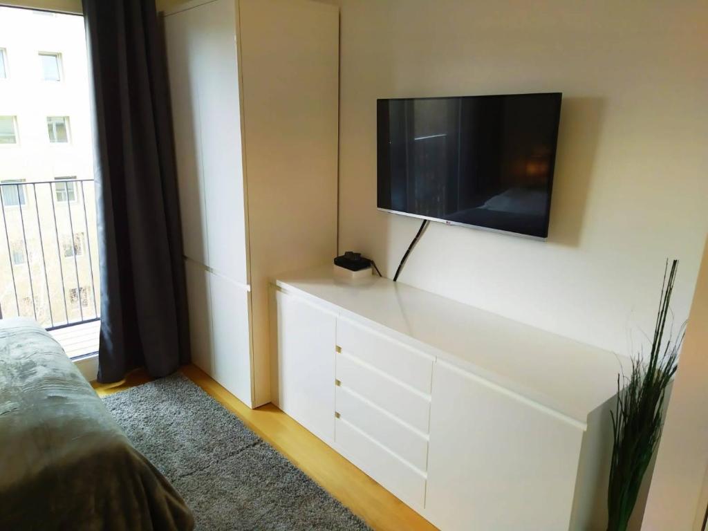 eine weiße Kommode mit einem Flachbild-TV an der Wand in der Unterkunft Cosy Park Apartment City Center in Wien