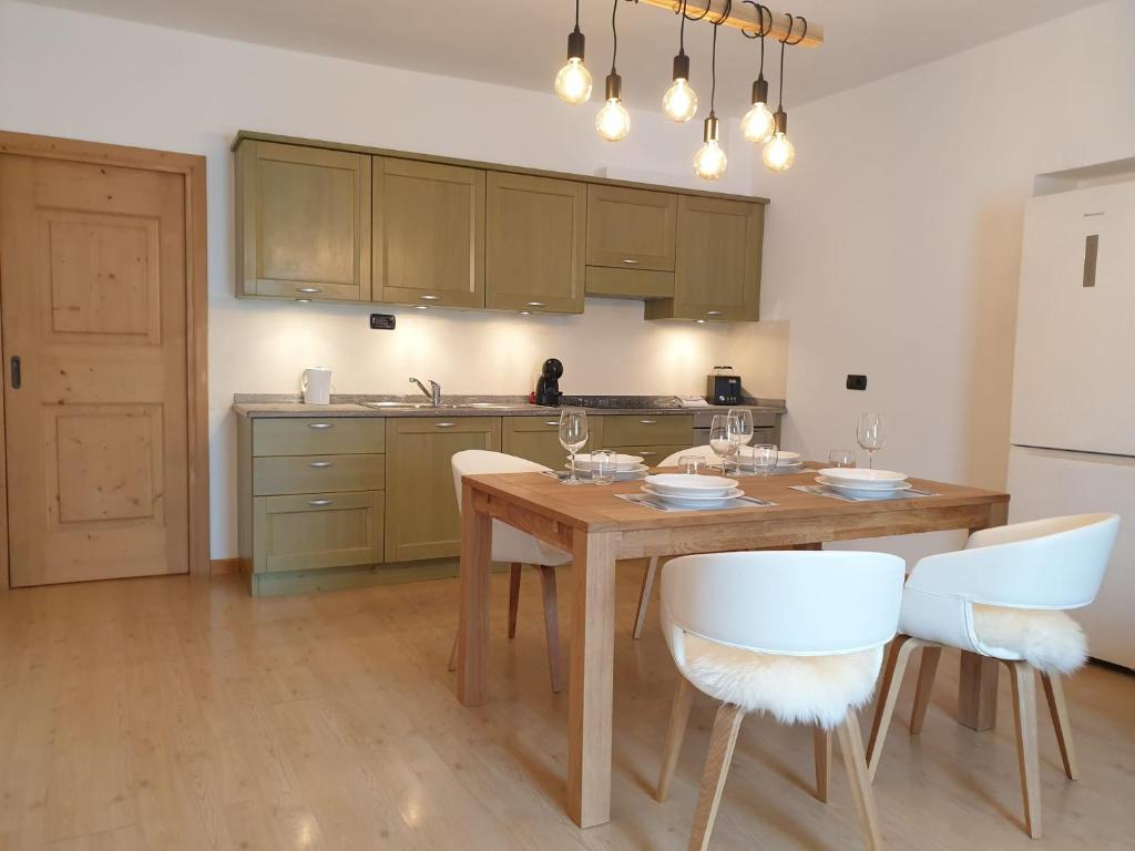- une cuisine avec une table en bois et des chaises blanches dans l'établissement CASA TANTI, à Bormio