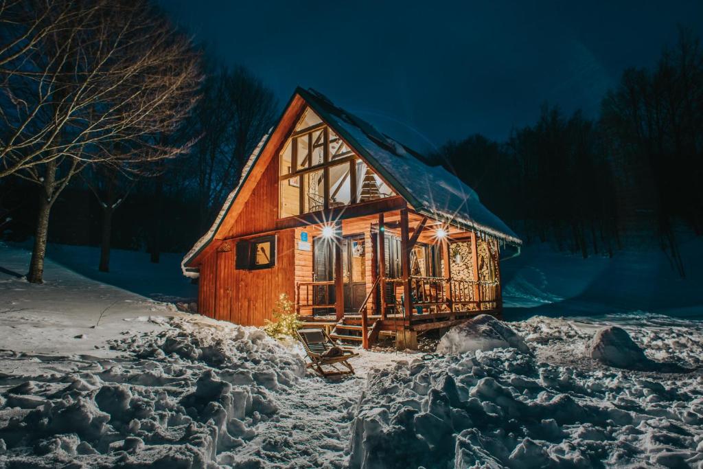 ムクロパイにあるKoliba Šume Pjevaju - robinzonski smjestaj, struja 12 V, voda iz cisterneの夜の雪の中のログキャビン