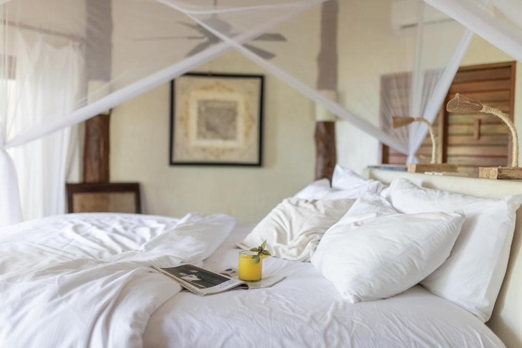 a white bed with a book and a drink on it at Encantada Tulum in Tulum