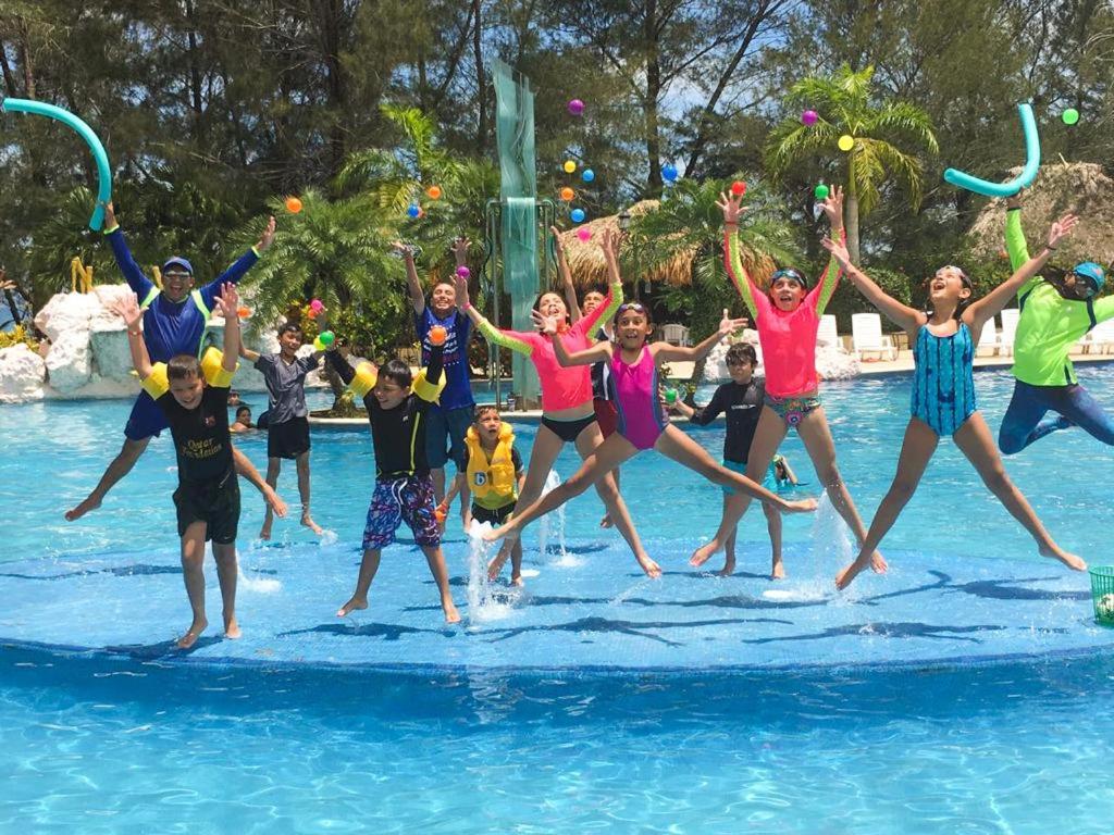 a group of people jumping in the water at a water park at La Ensenada Beach Resort in Tela