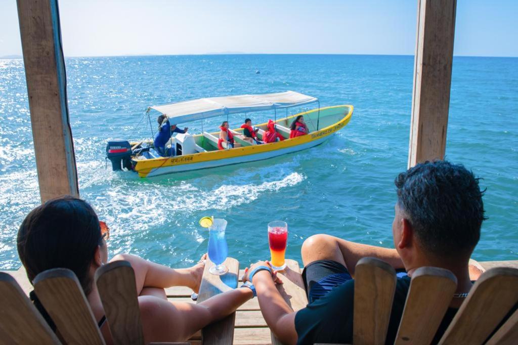 a group of people sitting on a dock with a boat at La Ensenada Beach Resort in Tela