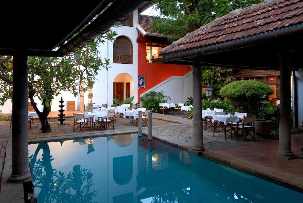 a pool with tables and chairs next to a building at Malabar House in Cochin